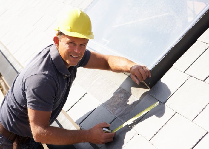 roof installation Rhode Island - contractor with measuring tape on roof in RI
