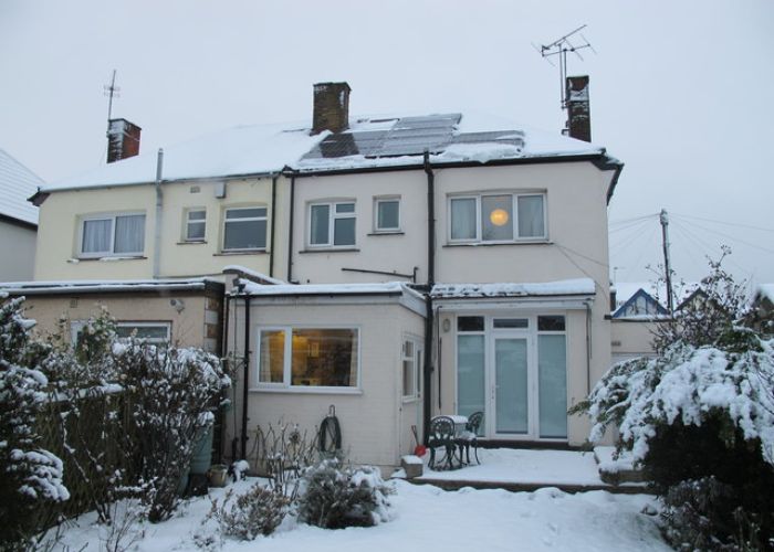 snow covered solar panels on residential home